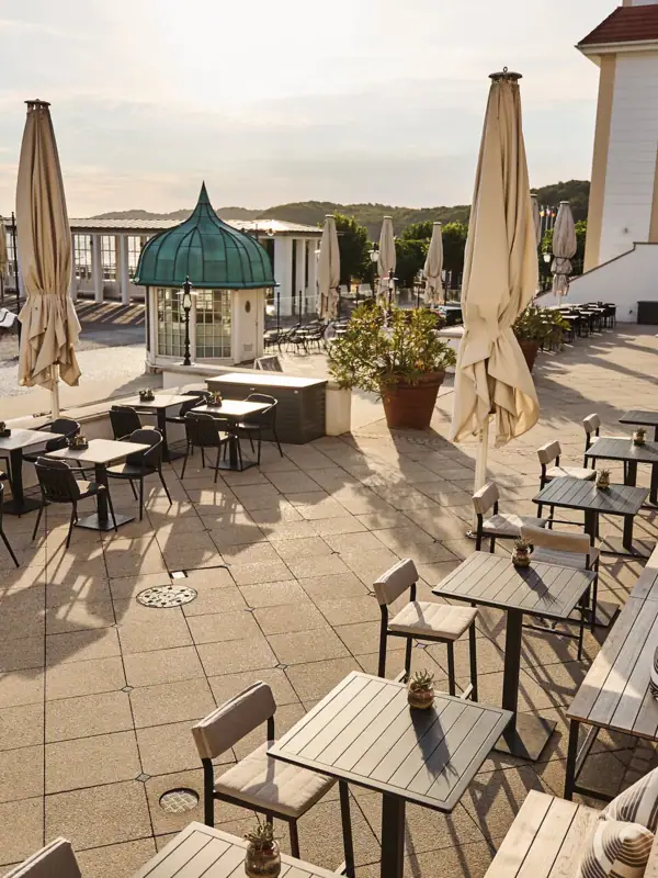 A patio with tables and umbrellas under a clear sky.