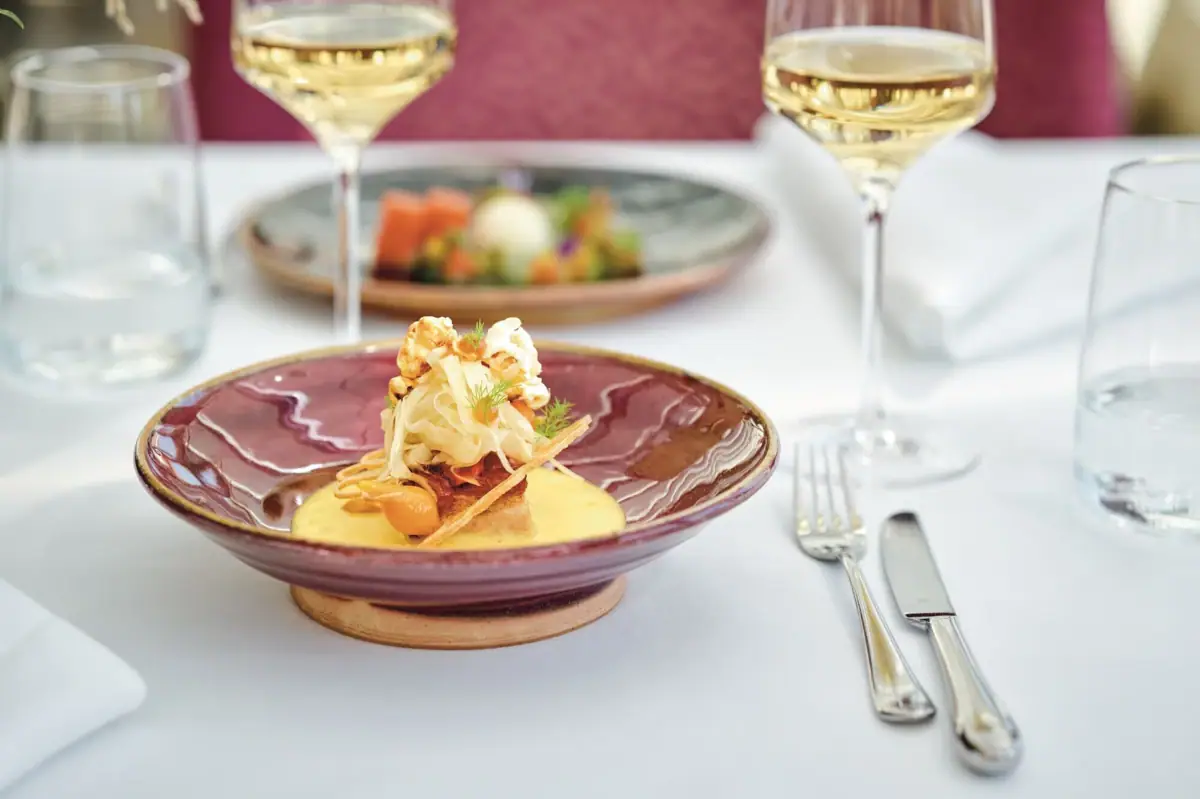 A plate of food accompanied by a wine glass on a table.