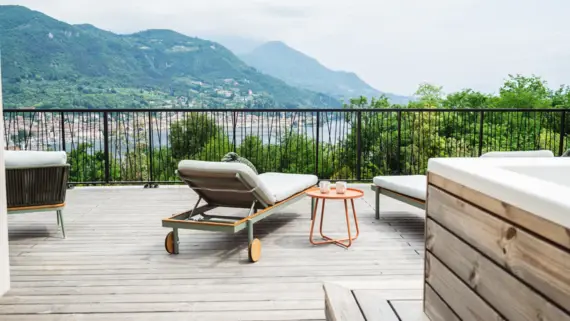 Terrace with chairs and a table, surrounded by plants and mountain views.