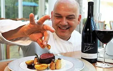 A man holding a piece of meat on a plate.