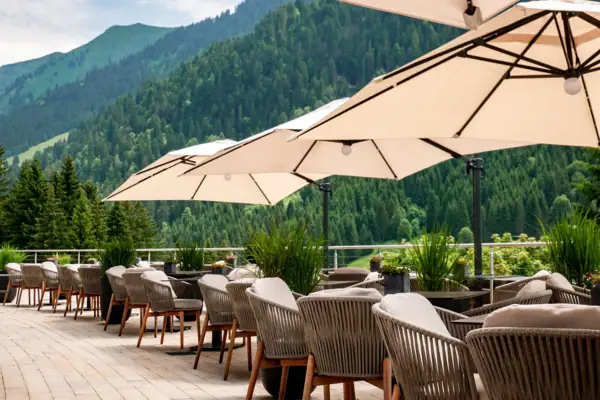 Terrasse Mehrere gemütliche Stühle und Sonnenschirmen auf einer Terrasse mit Bergen im Hintergrund.
