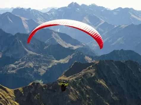 Person paragliding over a mountain landscape.