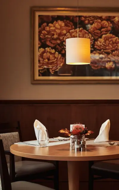 A table with a lamp and a floral decoration on it.