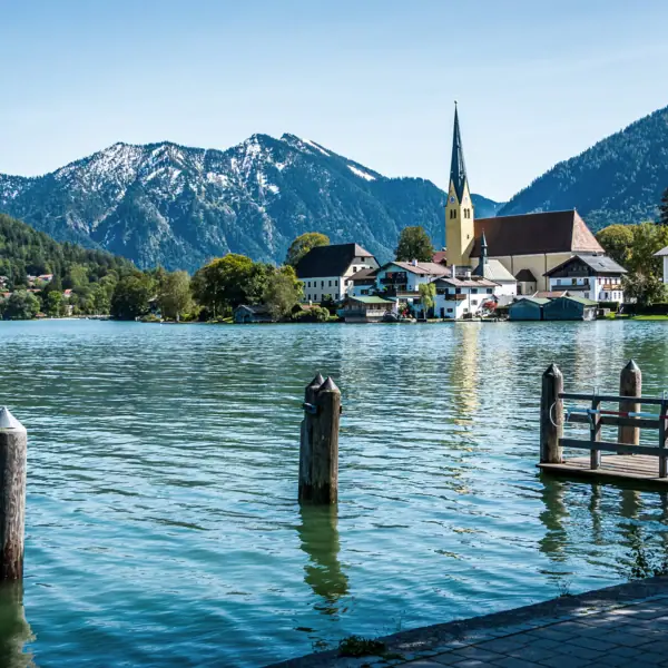 A lake with a church and mountains in the background.