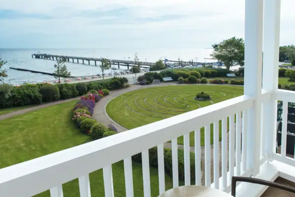 A balcony overlooking a garden and pier with a clear sky.