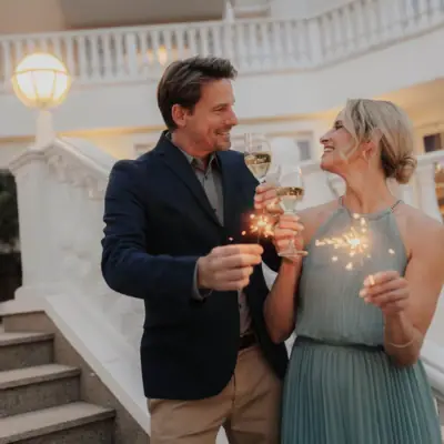 A man and a woman are holding wine glasses and smiling.