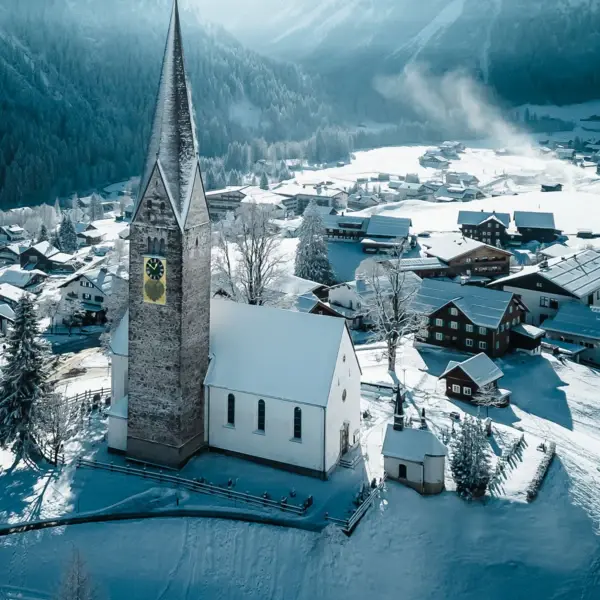 Church in a snowy town with mountains in the background.