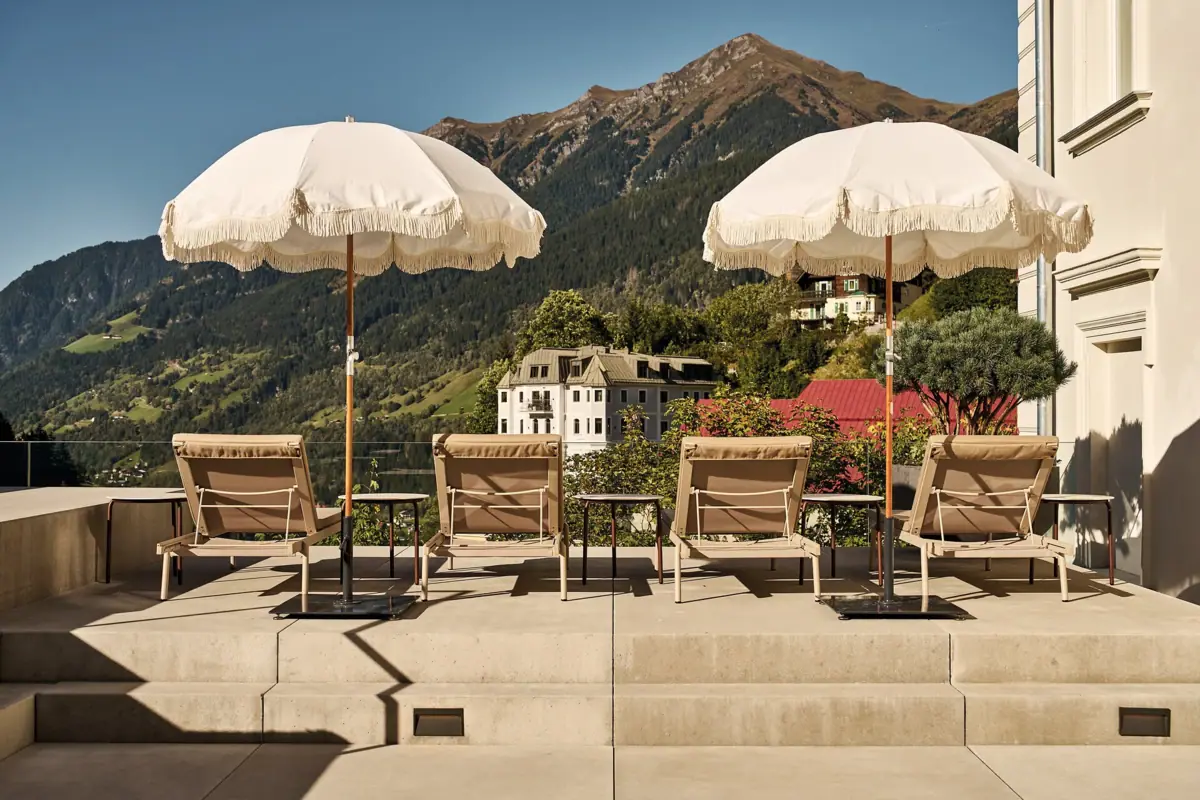 Pool area at the A-ROSA Straubinger Grand Hotel Bad Gastein A group of chairs and parasols on a terrace.