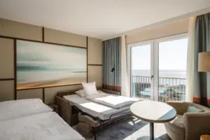 A room with a bed, chairs and a table.
