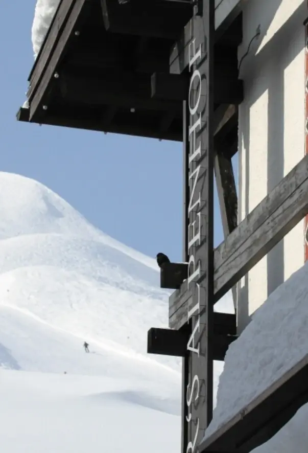 A house wall with a snow-covered mountain in the background.