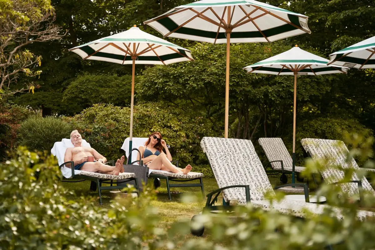 Ein Mann und eine Frau sitzen auf Liegestühlen unter Sonnenschirmen.