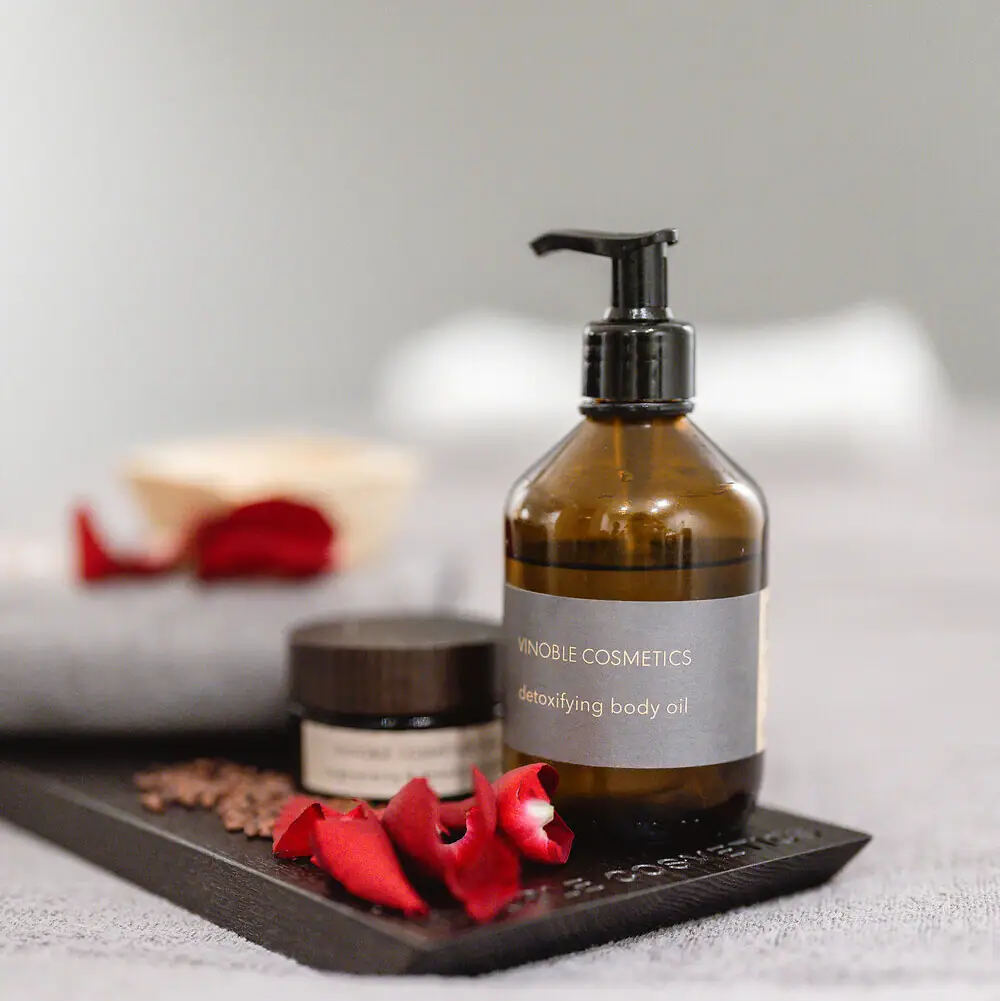 A bottle of body oil and a jar of cream on a tray.