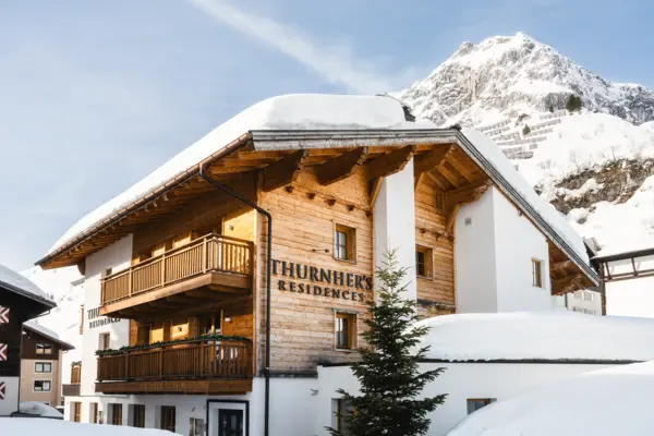 A house with the inscription Thurnher's Residences stands in the snow and a snow-covered mountain can be seen in the background.