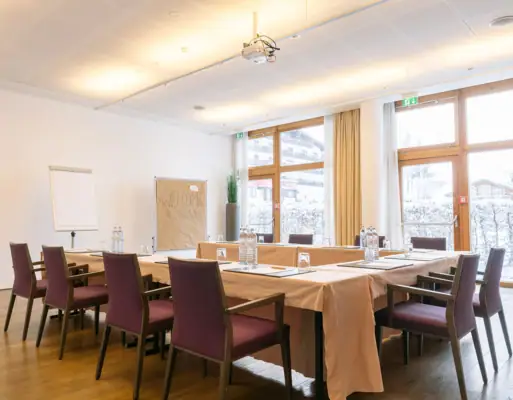 Ein heller Tagungsraum mit einem Tisch und Stühlen.