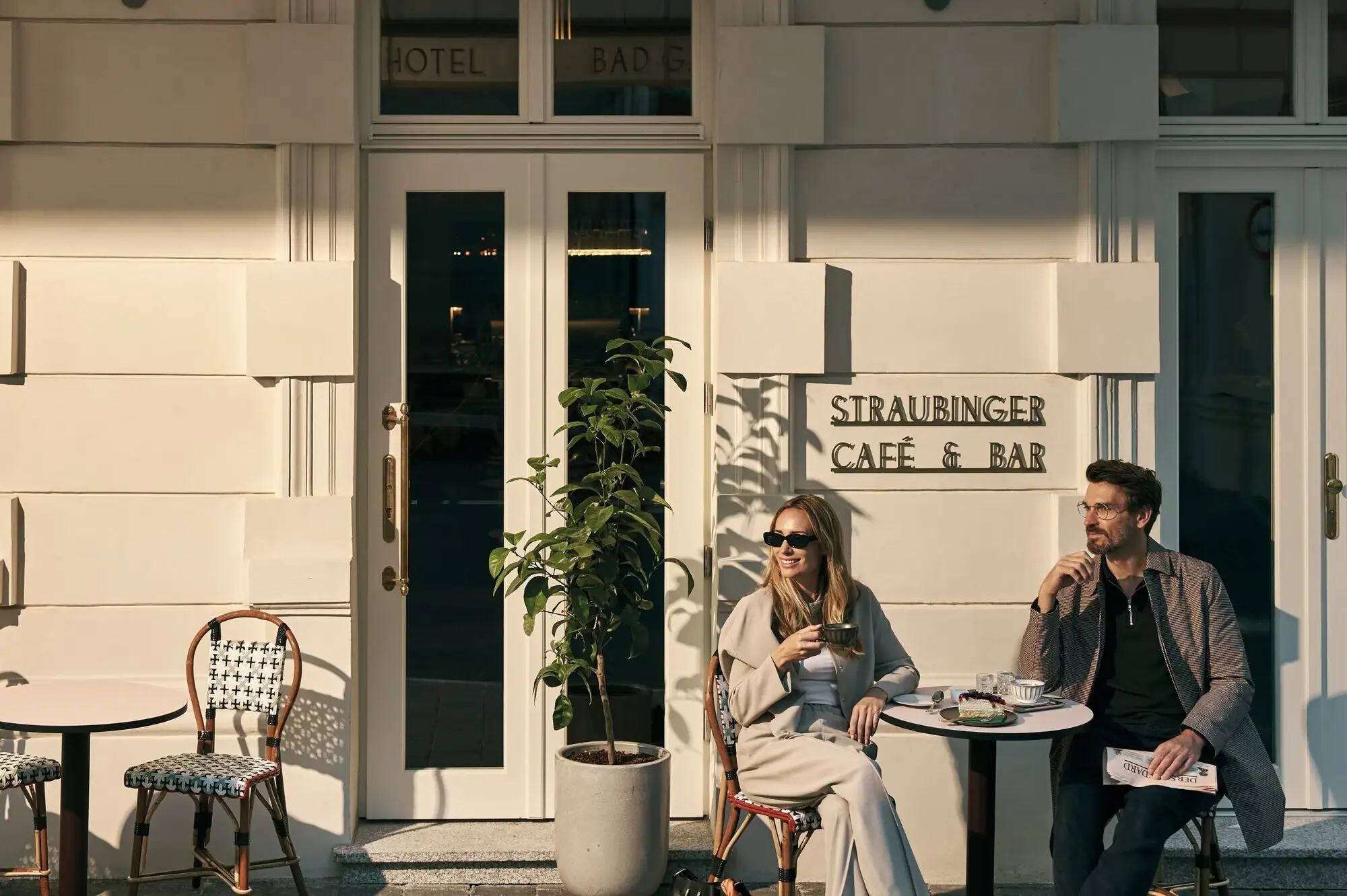 Guests enjoying Viennese coffee house culture on the terrace of Straubinger Café in Bad Gastein with waterfall backdrop.