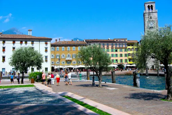 Riva del Garda A group of people are walking along a path near the water.