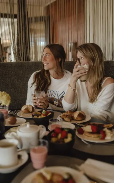 Two girls sitting at a breakfast table and enjoying a coffee. 