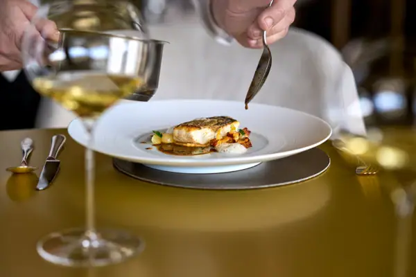 A person holding a spoon over a meal on a plate.