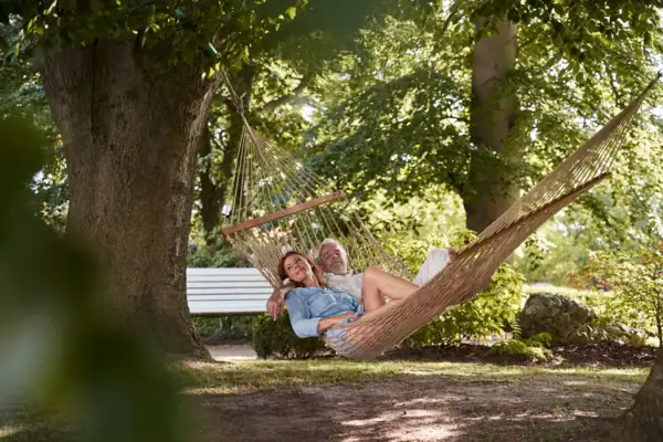 A man and woman relaxing in a hammock outdoors.