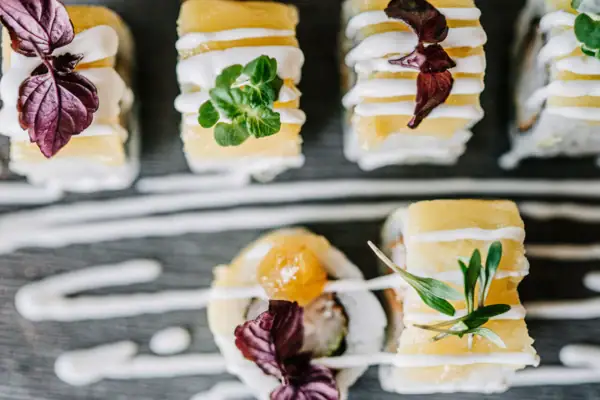 Ein Teller Sushi mit weißer Soße und Blumen.