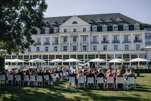 Eine Hochzeitsgesellschaft sitzt auf Stühlen bei einer freien Trauung vor dem A-ROSA Travemünde.