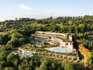 Building with pool surrounded by trees and a green landscape.