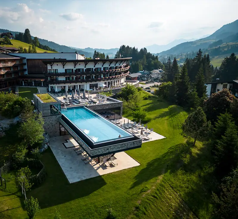 A-ROSA Ifen Hotel Kleinwalsertal Outdoor pool of a hotel with a view of trees and sky.