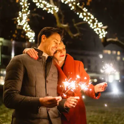A man and a woman are holding sparklers.