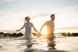 Ein Mann und eine Frau halten sich im Wasser an den Händen.