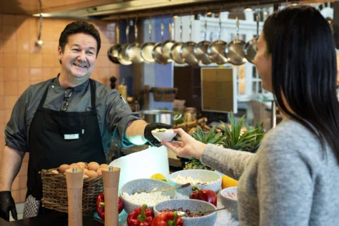 A man hands a woman a bowl of food.