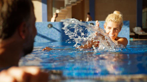 A woman swimming in a pool, water splashing around her.