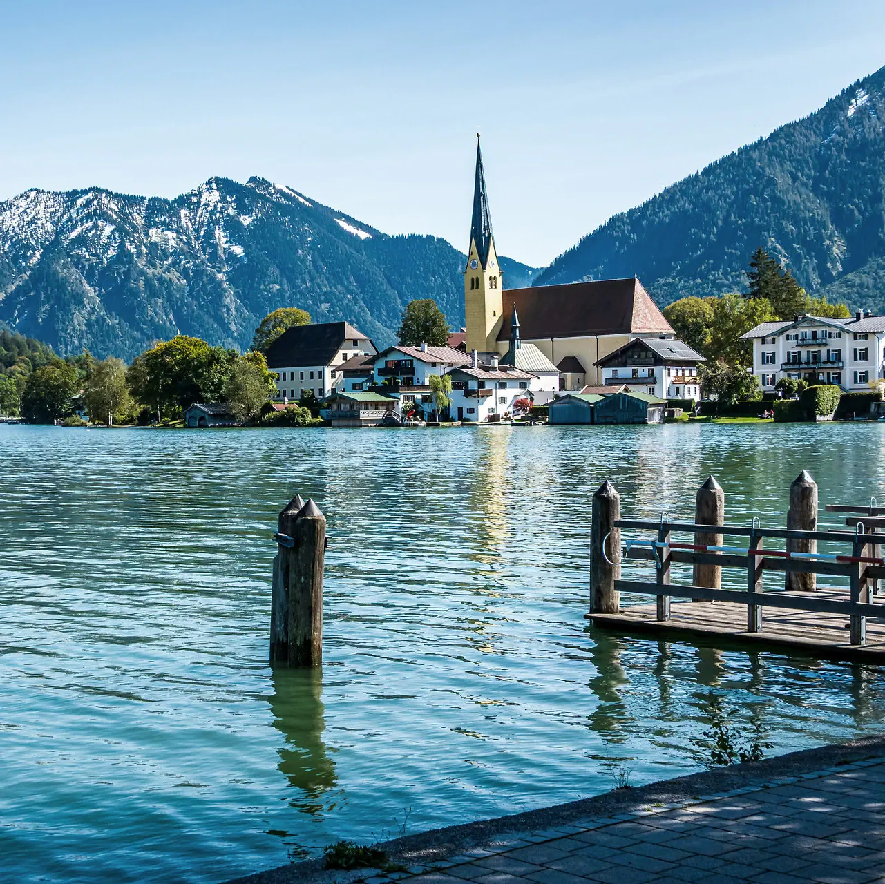 A lake with a church and mountains in the background.