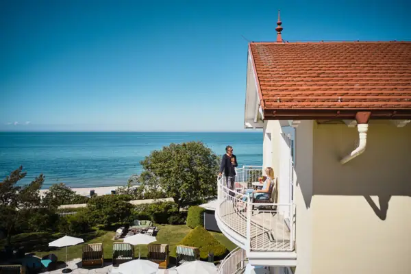 A couple of people on a balcony overlooking a beach with a view of the sky and water.