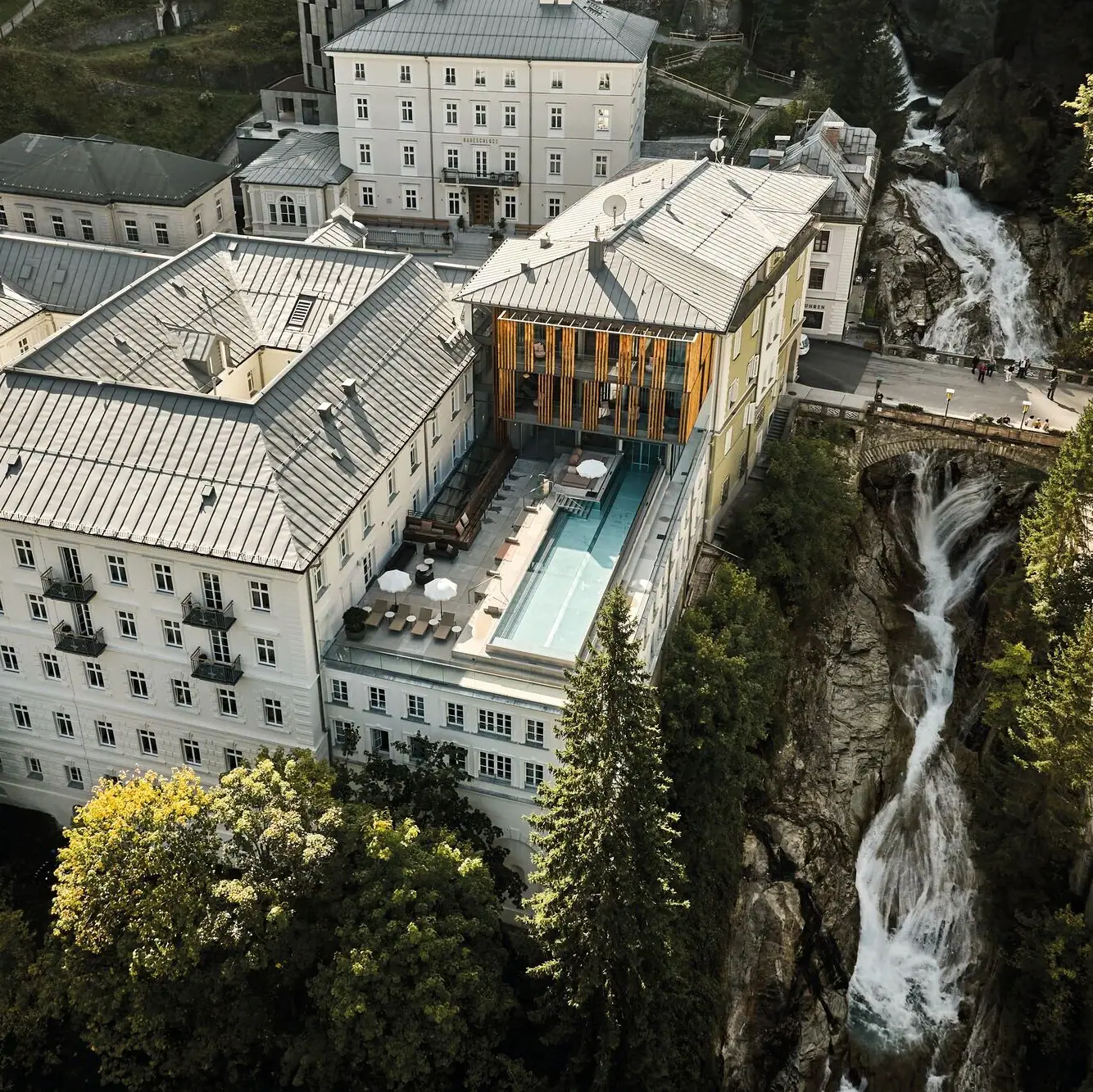 Ein Gebäude mit Pool und Wasserfall im Freien, umgeben von Bäumen.