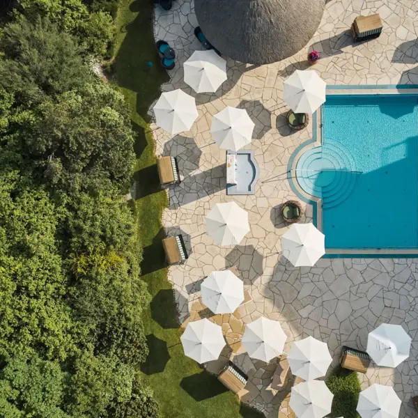 An aerial view of an outdoor pool surrounded by parasols and sun loungers.