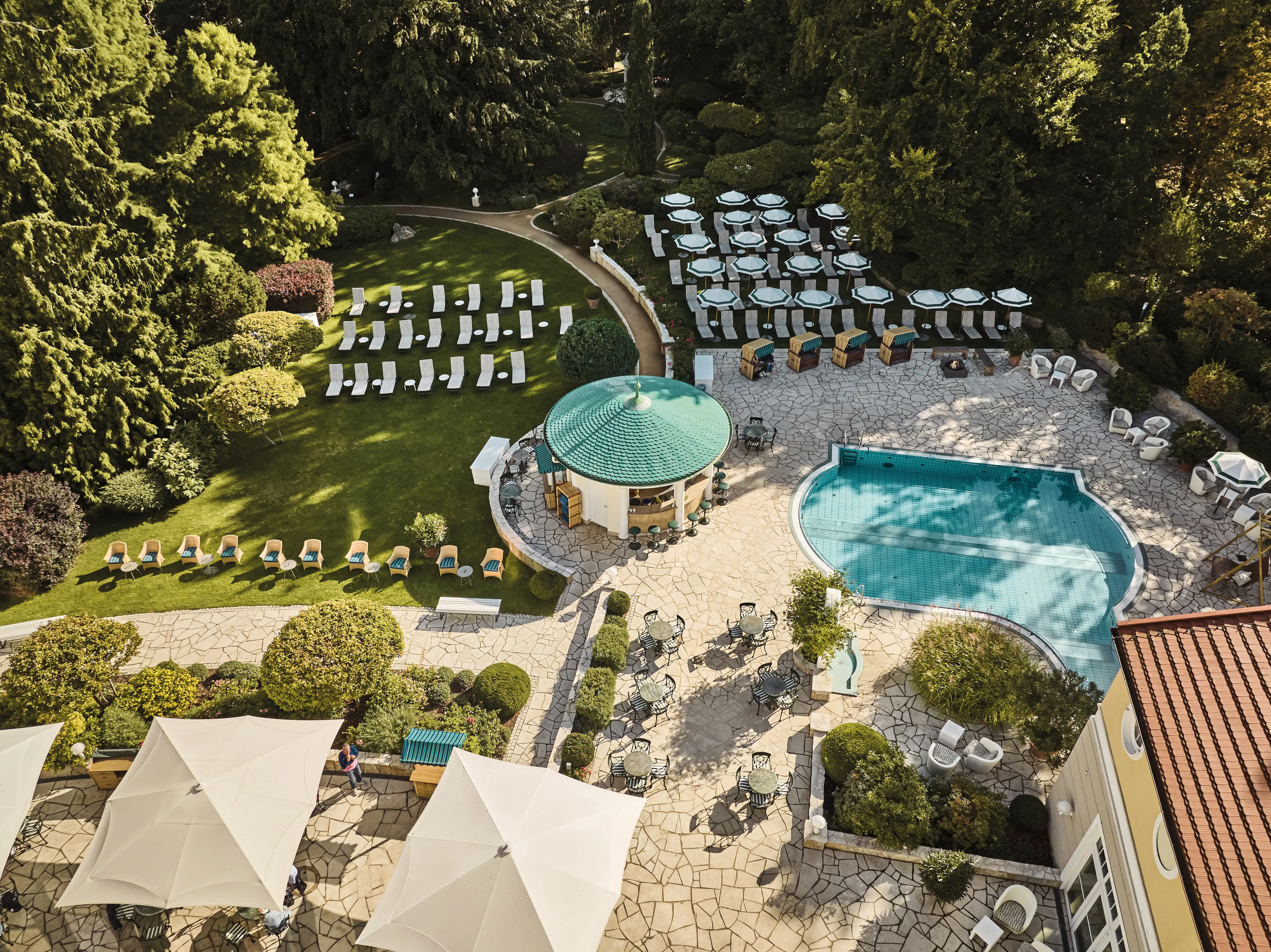 Swimmingpool und Stühle in einem Garten umgeben von Bäumen und Pflanzen.