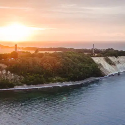 Baltic Sea A lighthouse on a hill overlooking a body of water under a cloudy sky.