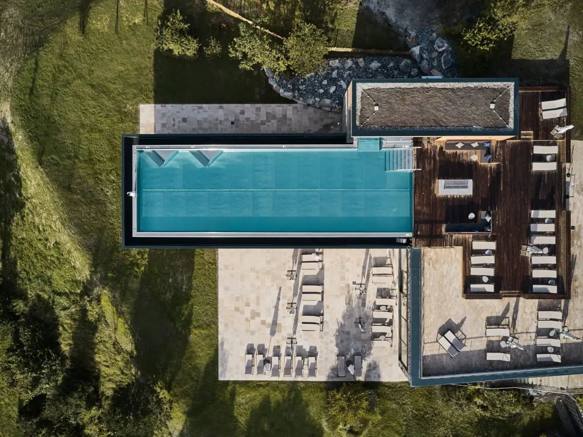 Pool auf einem Gebäude mit Bäumen drum herum aus der Vogelperspektive.
