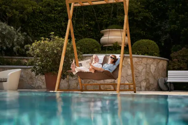 A man and woman lying on a swing outdoors.