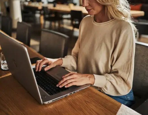 A woman sitting at a table using a laptop indoors.