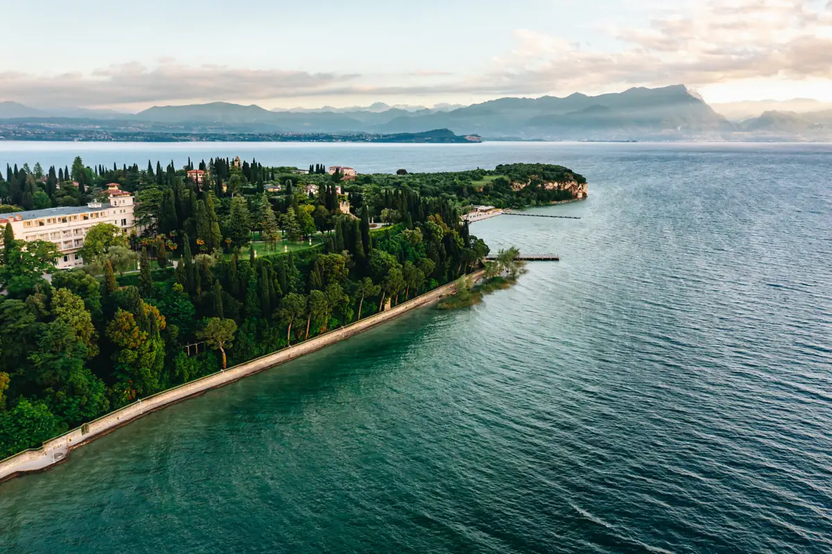 Ein Gewässer mit einer kleinen Insel, auf der Bäume und Gebäude stehen.
