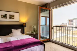 Bedroom with open balcony access and elegant bed.