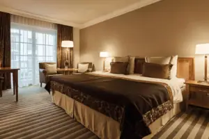 A bed with a bedside lamp and a table in a stylishly furnished room.
