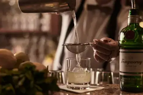 A person is pouring a drink into a glass.