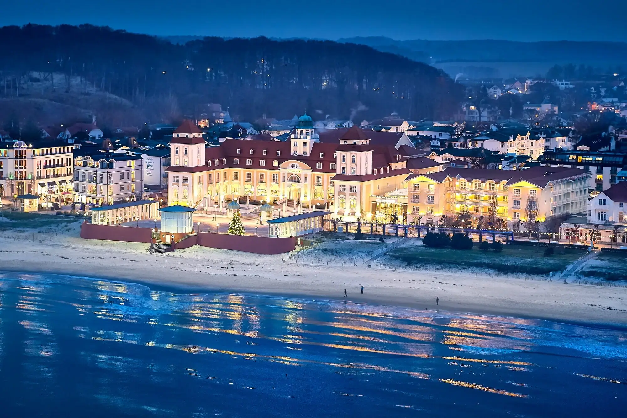 Illuminated A-ROSA Kurhaus Binz on the sandy beach of Rügen at twilight.