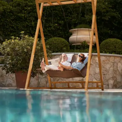 A man and woman lying on a swing outdoors.