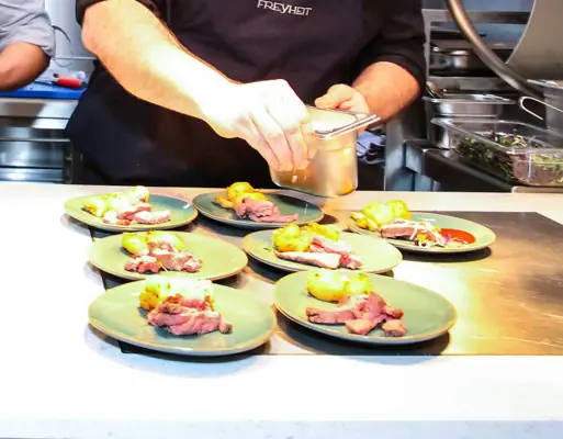 Freyheit Restaurant Two men in a kitchen preparing food.