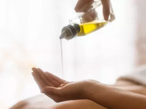 A person indoors pouring oil onto their hand.