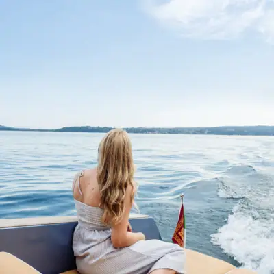 A woman sitting on a boat surrounded by water under a cloudy sky.