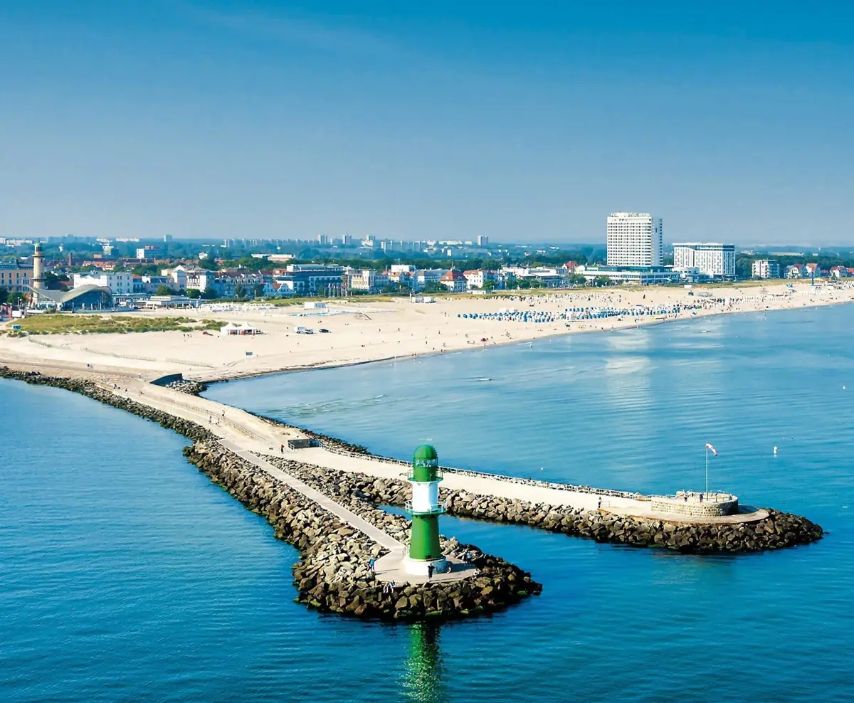 Grüner und weißer Leuchtturm auf einer felsigen Insel.